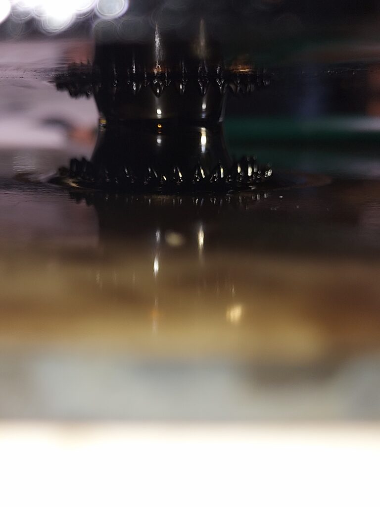 A shorter, wider ferrofluid bridge joins two glass panes, surrounded by pointed peaks at the top and bottom.